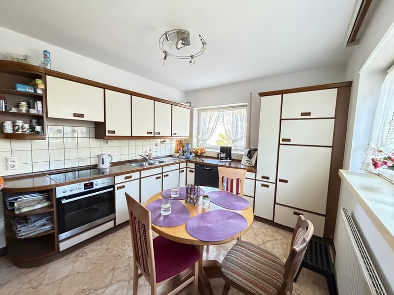 kitchen with dining area, white cabinets, wooden table, chairs, oven, sink, dishwasher, washing machine, window with curtains