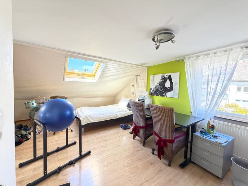 bedroom with bed, desk, chairs, exercise ball, drum set, skylight, green wall, white curtains