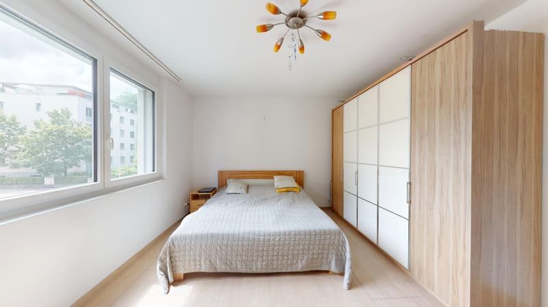bedroom with bed, nightstand, large window, wooden wardrobe, chandelier