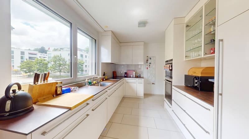 modern kitchen with white cabinets, tiled floor, large window, countertop, sink, oven, refrigerator, kettle, chopping board, knives
