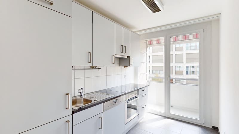 modern kitchen with white cabinets, stainless steel sink, dishwasher, oven, granite countertop, sliding glass door to balcony