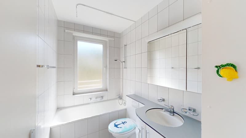 Bathroom with white tiles, bathtub, toilet, sink, mirror, and shower head.