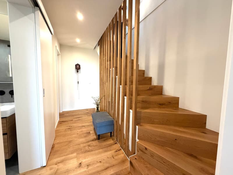 wooden stairs, wooden floor, blue ottoman, white walls, white door, bathroom sink