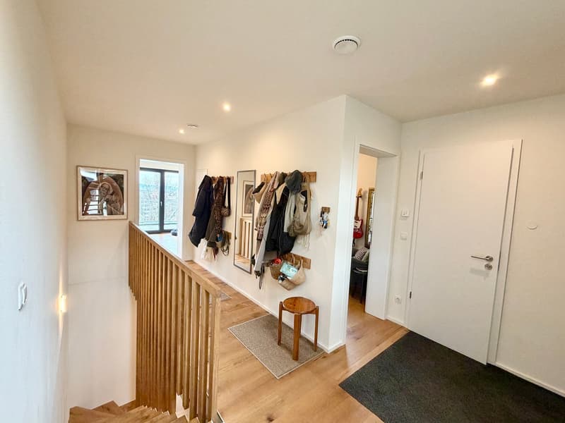 wooden staircase, wooden floor, white walls, coat rack, picture frame, stool, rug, door