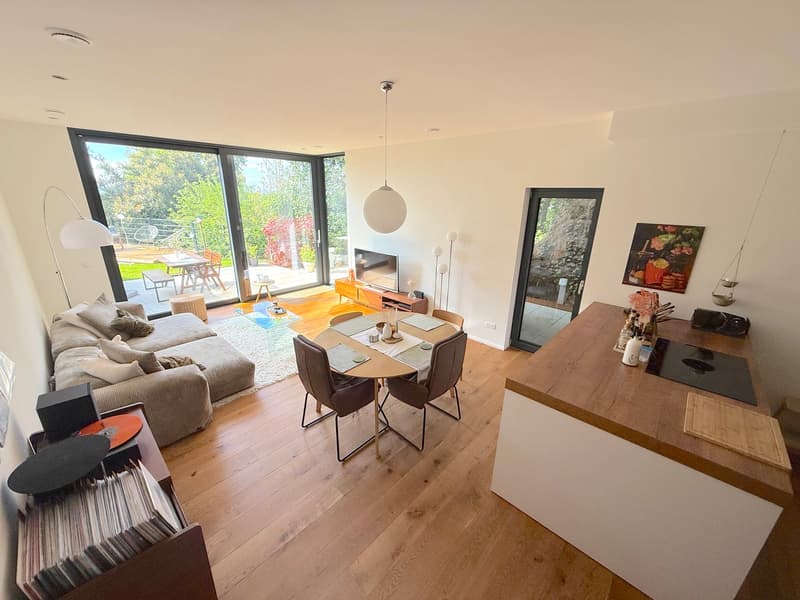 Open plan living room and dining area, large windows, wooden floor, modern furniture, balcony, view of the garden