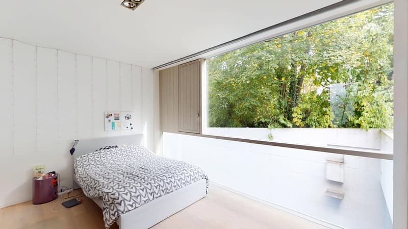 white walls, wooden floor, bed, large window, view of trees