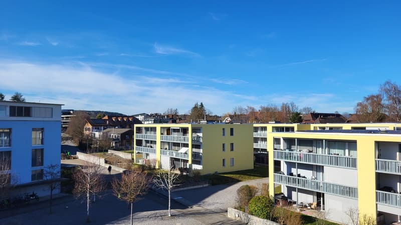 Aerial view of a residential building complex with multiple buildings, balconies, and a parking area.