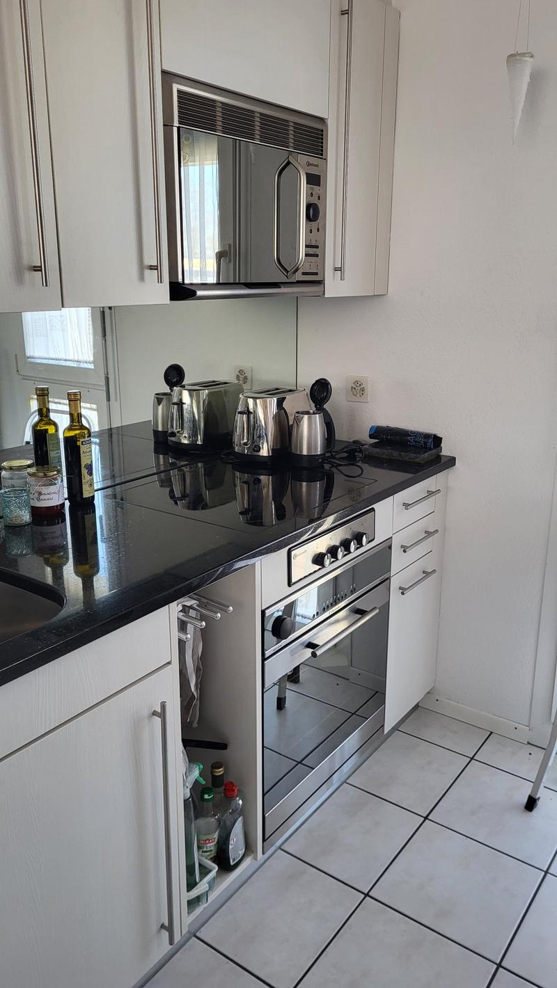 modern kitchen with white cabinets, black countertops, stainless steel appliances, and a dishwasher