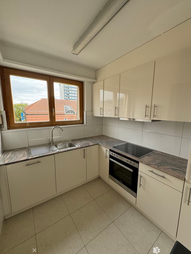 Modern kitchen with white cabinets, granite countertops, stainless steel sink, and a gas stove.