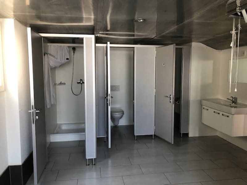 Modern design with three cubicles, a separate shower, a toilet, and a sink.