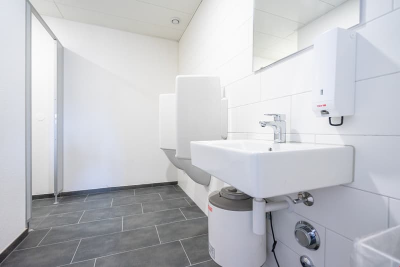A bathroom with a square sink, 2 urinals, and tiled flooring
