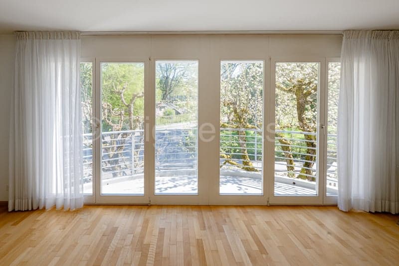 large sliding glass doors, wooden floor, white curtains, balcony, view of trees