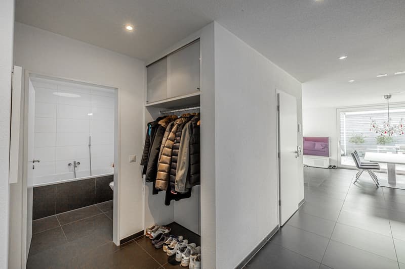 Entrance hall with a wardrobe, shoes, and a bathroom with a bathtub and toilet