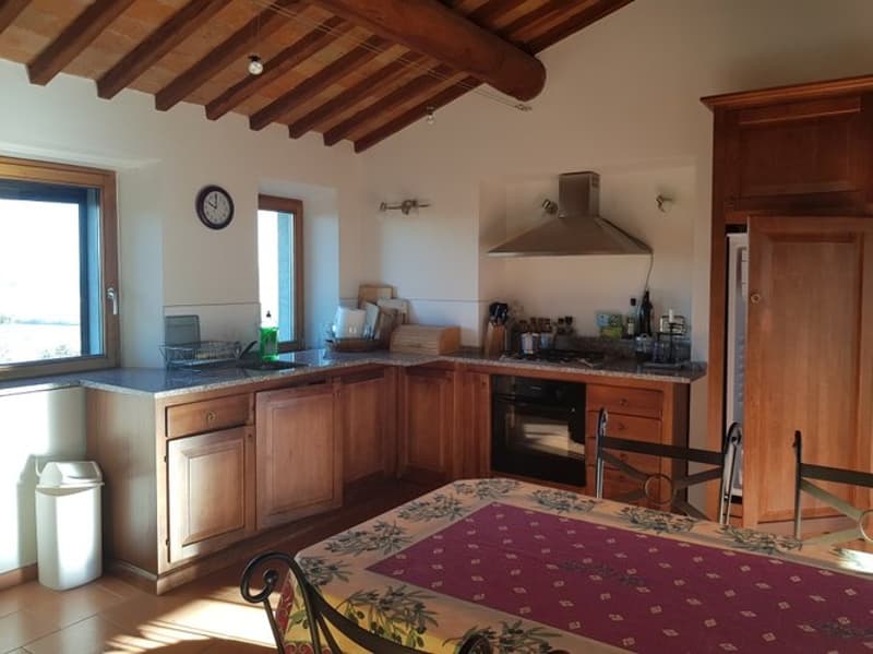 Rustic kitchen with wooden beamed ceiling, wooden cabinets, granite countertops, stove, dishwasher, and washing machine