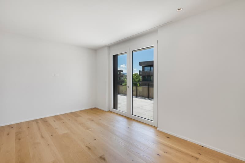 Spacious room with hardwood flooring, large windows, and access to a balcony or terrace.