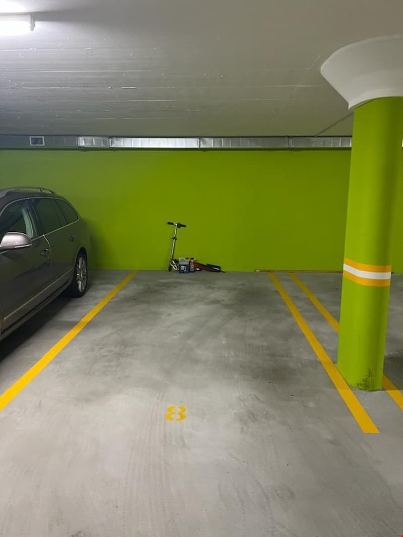 Underground parking with green walls, yellow parking lines, pole with yellow stripes