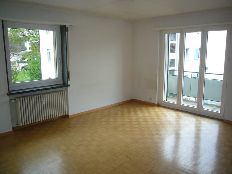 empty room, wooden parquet floor, white walls, sliding door to balcony, window, heater