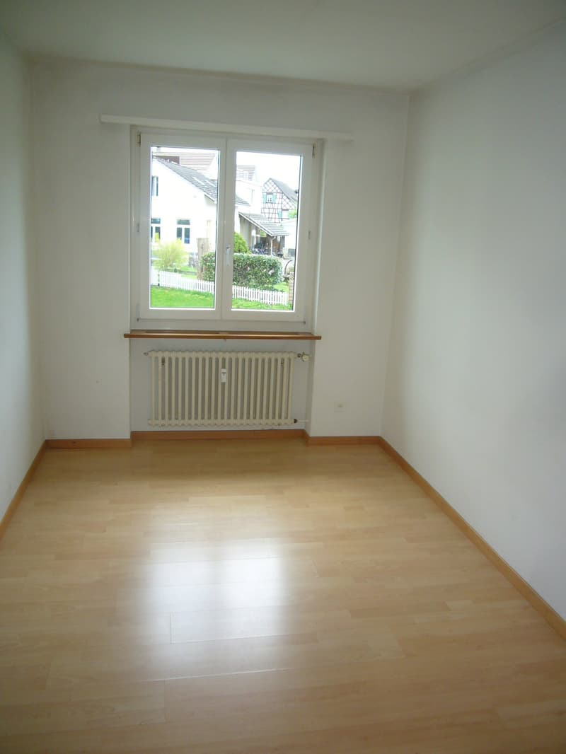 empty room, white walls, wooden floor, window with white trim, radiator under window