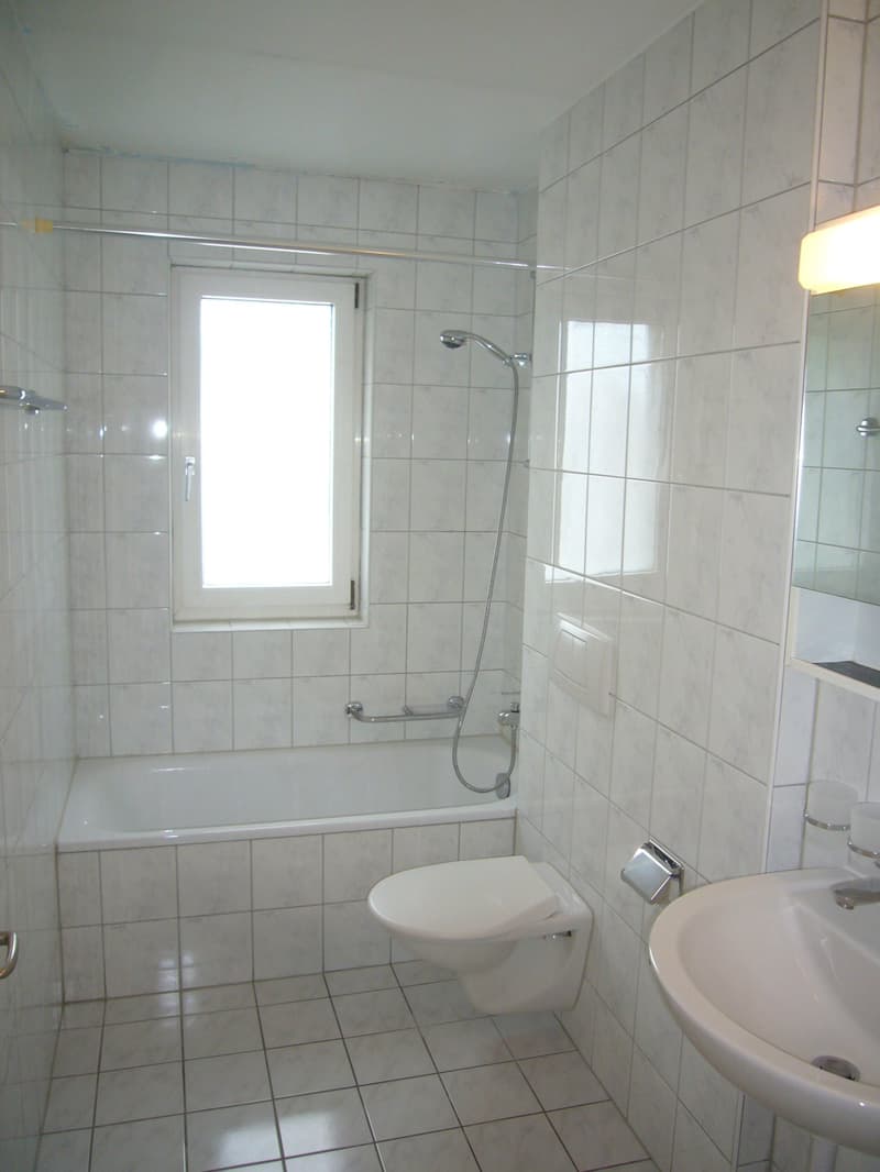 Bathroom with white tiles, bathtub, toilet, and sink