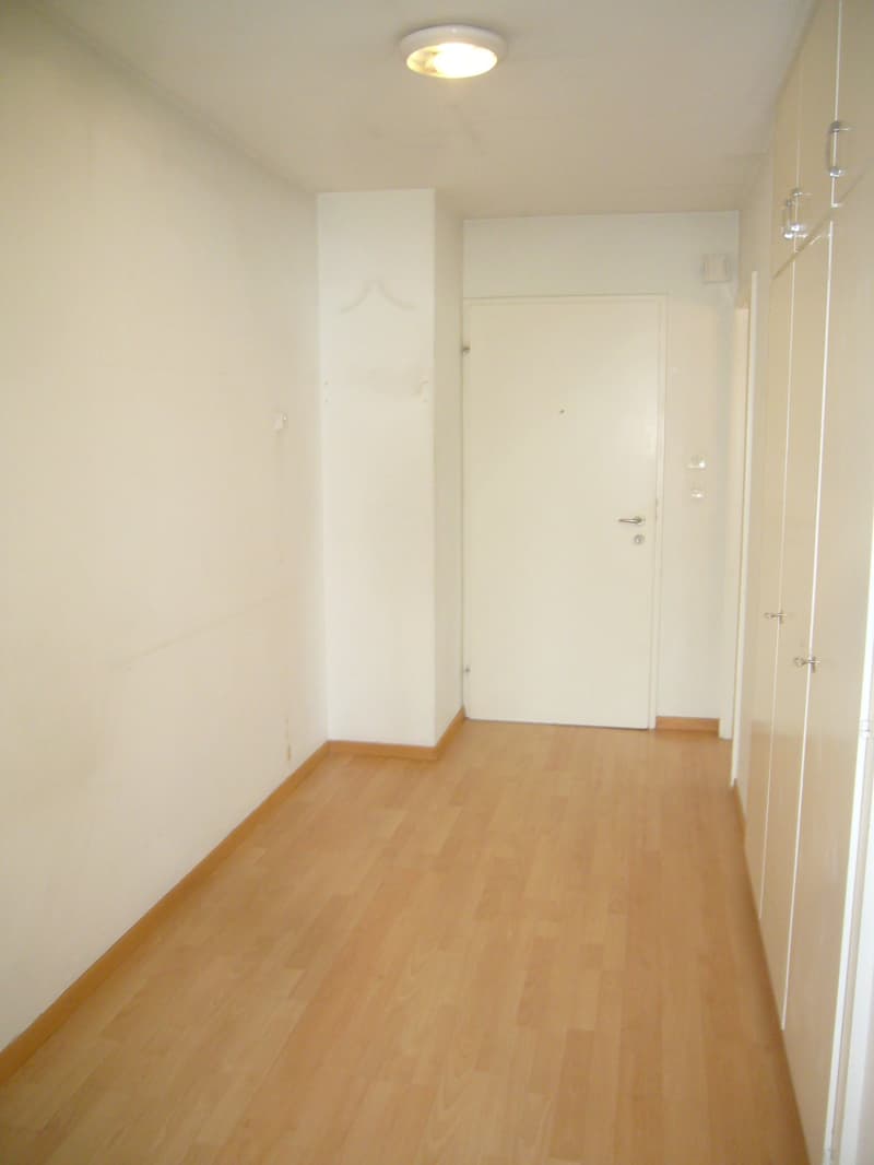 Empty room, white walls, wooden floor, closed door, ceiling light