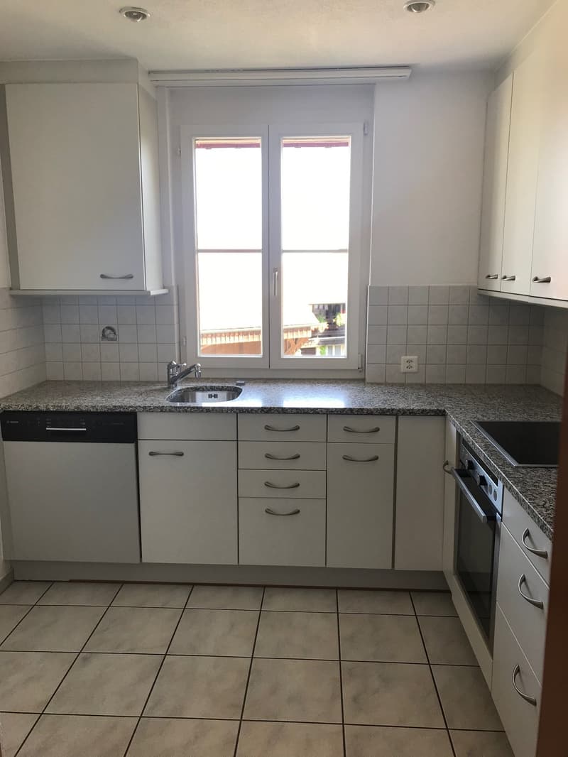 modern kitchen with granite countertops, white cabinets, stainless steel sink, dishwasher, washing machine, granite flooring, large window