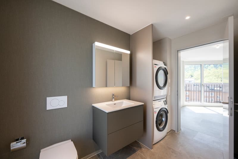 Gray wall, toilet, mirror, washing machine, and dryer