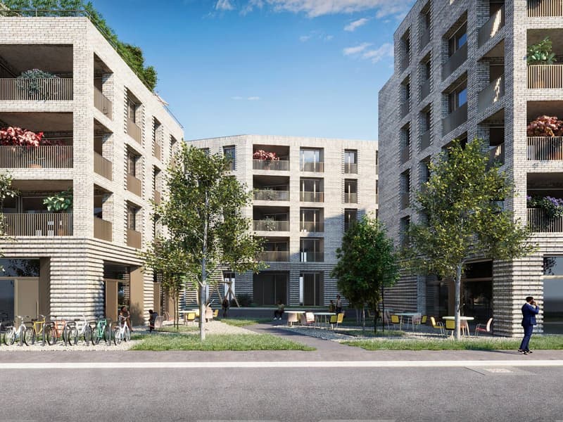 Multi-story apartment building with brick facade, balconies, and outdoor seating area with trees and greenery
