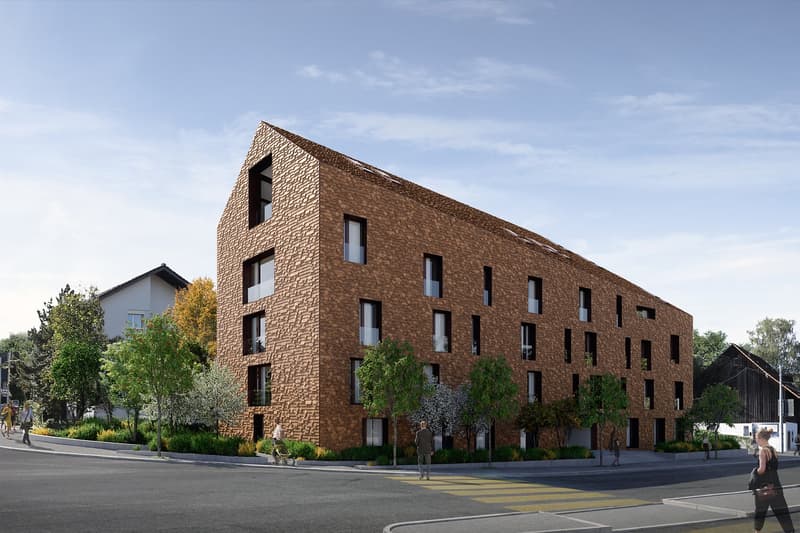 Modern apartment building with brown brick facade, multiple windows, and a triangular roof design.