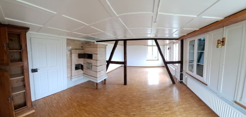 Spacious living room with hardwood floors, exposed wooden beams, a large fireplace, and built-in shelving units.