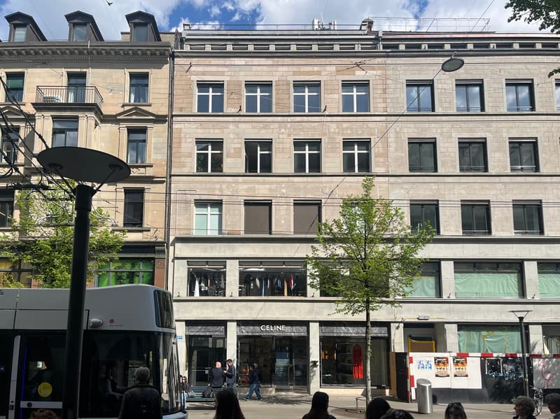 A large building with multiple windows and a bus parked in front.