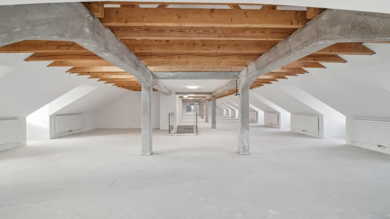 empty attic with concrete floor, exposed wooden beams on ceiling, central staircase, heating units
