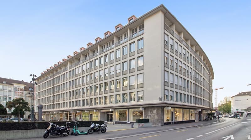 6 story building, beige exterior, glass windows, ground floor with shops, balconies
