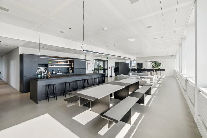 modern office space with a large counter, stools, tables, benches, and plants