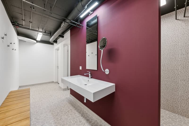 Bathroom with a white sink, a mirror, a wooden bench, and a red wall