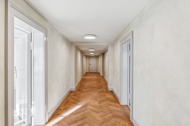 long hallway, white walls, wooden floor, white doors, recessed lighting