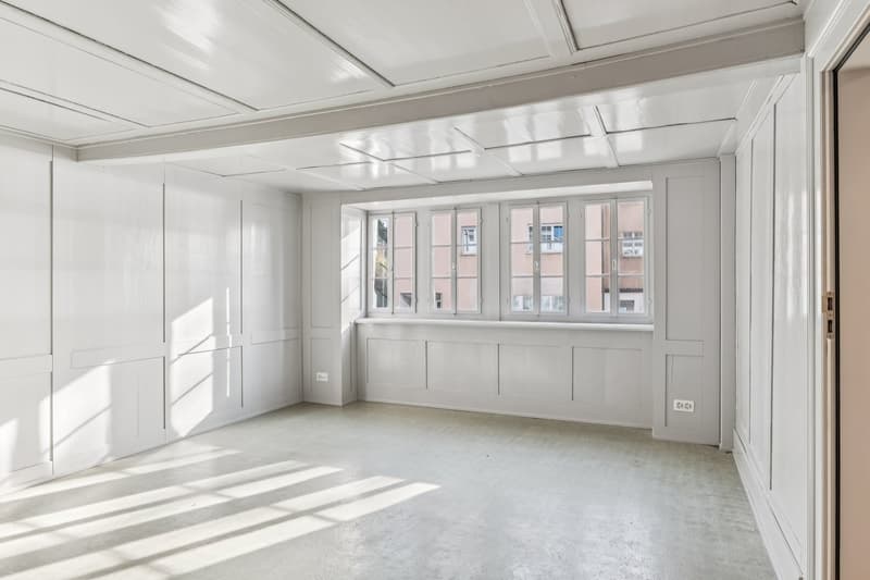 Empty room with white walls, white ceiling, white floor, large window with view to the outside