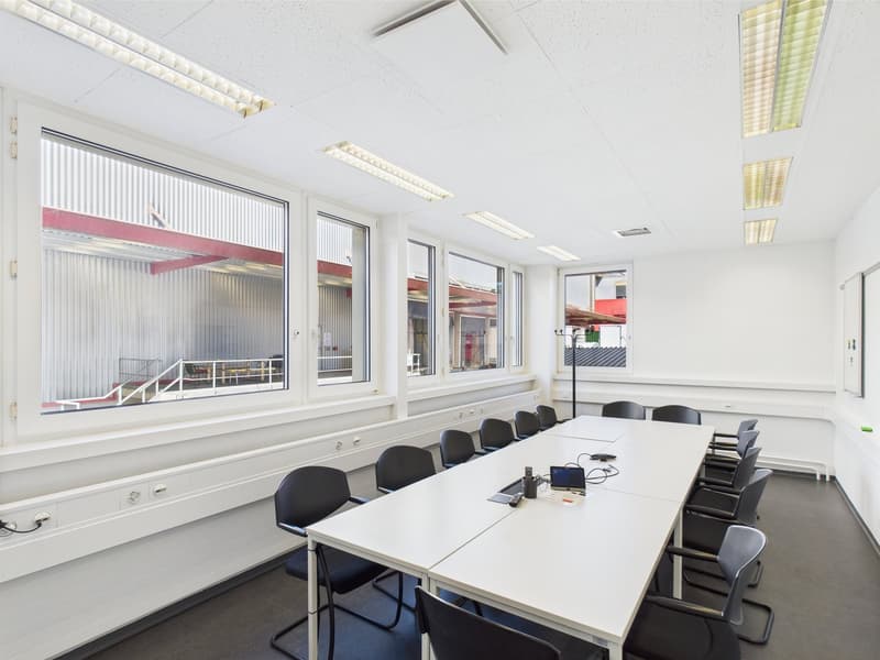 Large conference room with white walls, white table, black chairs, and large windows overlooking the exterior.