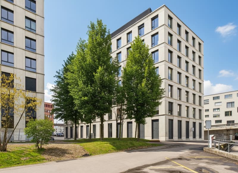 Multi-story building with glass windows, garages on the ground floor, trees, greenery, and a parking lot in front