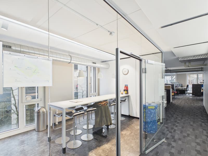 glass walls and doors, long white table, metal chairs, trash bin, whiteboard, clock on wall
