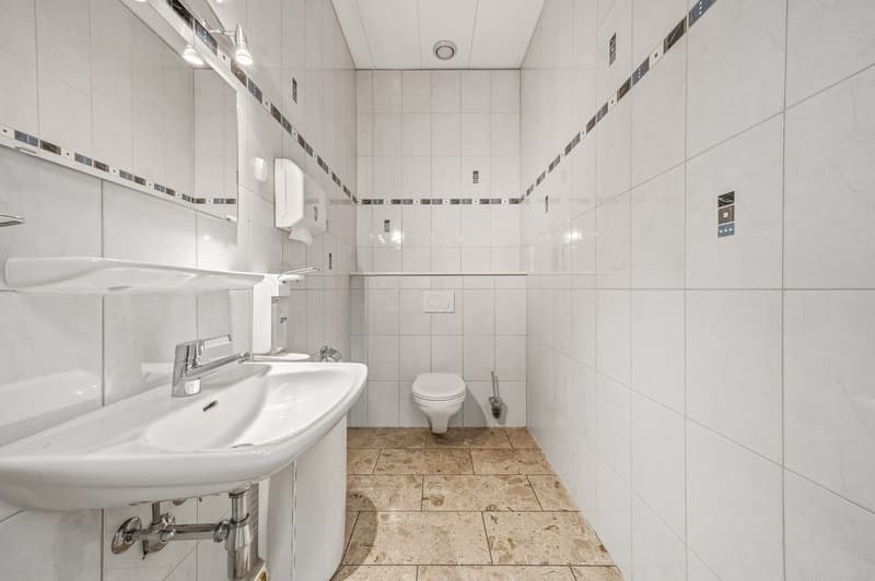 small bathroom with white tiles, sink, toilet, and a mirror