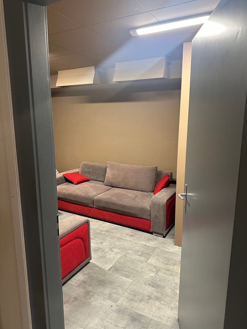 Red and grey couch, wooden floor, open door