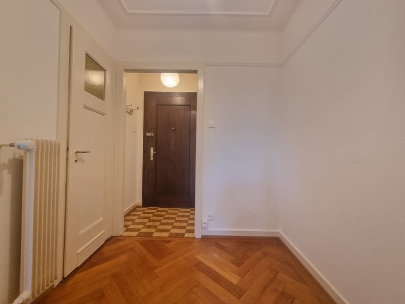empty hallway, wooden floor, radiator, doorway, brown interior door