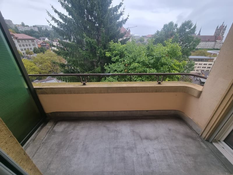 Terrace with city view, balcony railings, green curtains, floor covered with dirt.