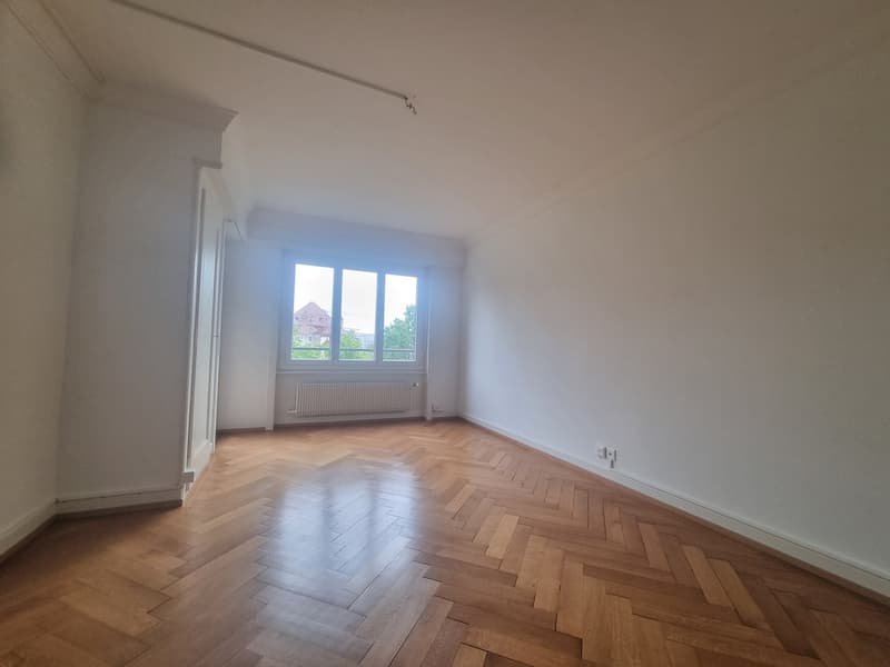 wooden parquet flooring, white walls, large window, white radiator, power outlet, hallway