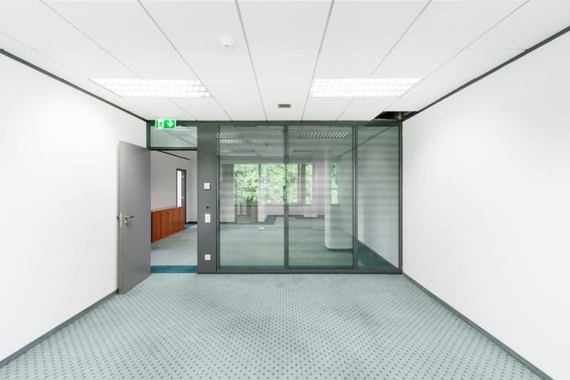 an empty office space with a glass wall, open door, and white walls