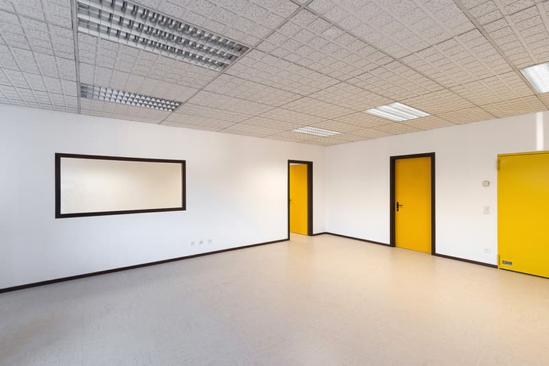 empty room with white walls, tile flooring, square windows and a door