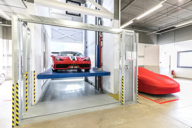 a red sports car on a lift inside an automotive facility