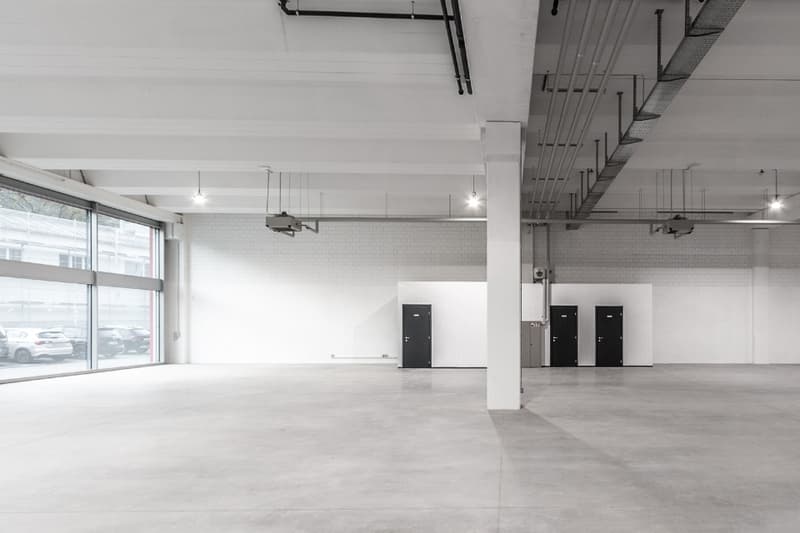 large room, concrete floor, glass walls, white walls, doors, metal beams, windows, lamps
