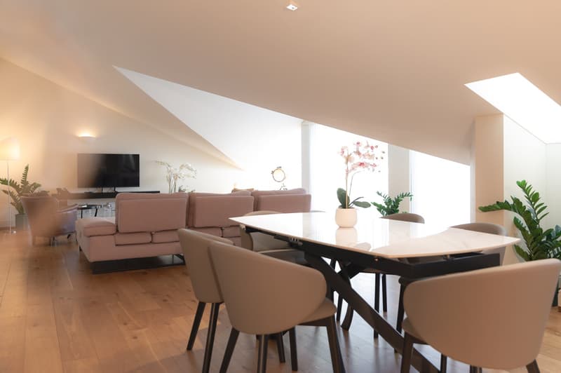 dining table with flower vase, chairs, beige couch, living area with tv, large windows