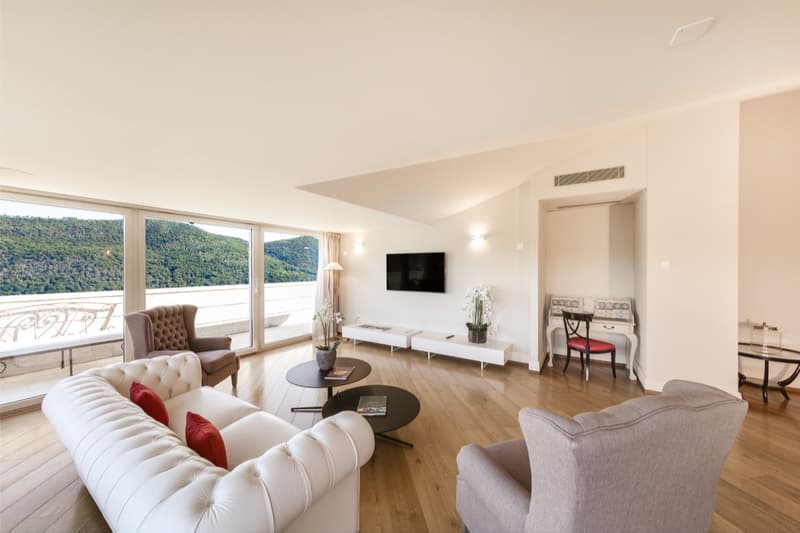 wooden floors, large windows with balcony, furniture including sofas and tables, TV, white walls, table with flowers, office desk, modern decor